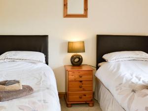 a bedroom with two beds and a night stand with a lamp at Mill Barn in Burnsall