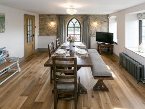 a dining room with a table with chairs and a television at The Old Church in Ashover