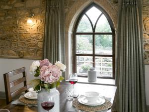 einen Tisch mit einer Vase aus Blumen und einem Fenster in der Unterkunft The Old Church in Ashover