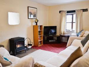 a living room with a fireplace and a tv at Moorland Retreat in Barbrook