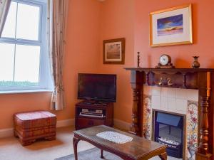 a living room with a fireplace and a tv at Shingle Cottage in Seascale