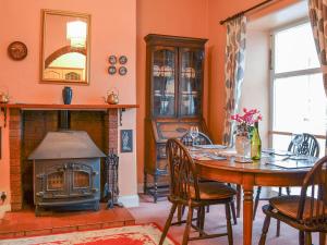a dining room with a table and a wood stove at Shingle Cottage in Seascale