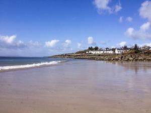 a beach with the ocean and houses in the background at Ben View in Gairloch