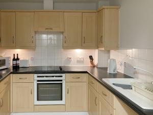 a kitchen with white appliances and wooden cabinets at River Side in Whitby