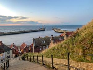 a view of the ocean with houses and a pier at River Side in Whitby