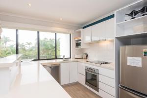 a kitchen with white cabinets and a large window at The Oasis Apartments and Treetop Houses in Byron Bay