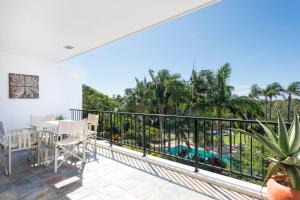 a balcony with a table and chairs and palm trees at The Oasis Apartments and Treetop Houses in Byron Bay