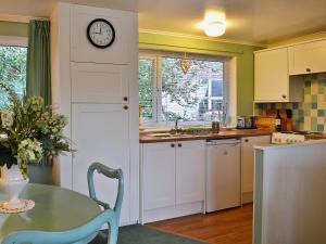 a kitchen with a table and a clock on the wall at Lake View in Bowness-on-Windermere