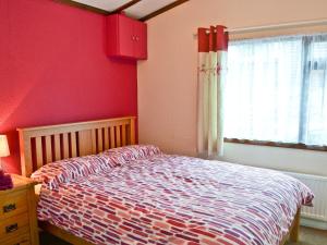 a bedroom with a bed and a red wall at Catbank in Bridekirk