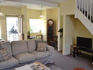 a living room with a couch and a clock at Woodburn Cottage in Soutergate