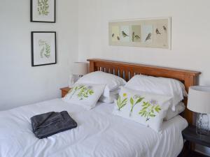 um quarto com uma cama com lençóis brancos e almofadas em Woodburn Cottage em Soutergate