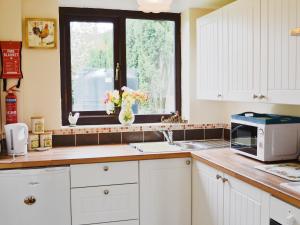 a kitchen with a sink and a microwave and a window at White Cottage in Hemingby