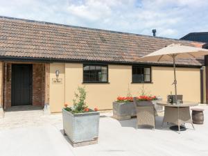 a patio with a table and an umbrella at The Old Dairy-ukc2112 in Royal Wootton Bassett