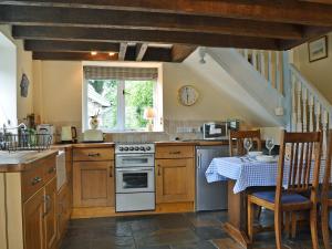 eine Küche mit einem Tisch und einem Herd Top-Backofen in der Unterkunft The Pigsty Cottage E2783 in Llanyblodwel