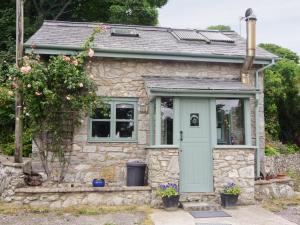 una pequeña casa de piedra con puerta azul en The Pigsty Cottage E2783 en Llanyblodwel
