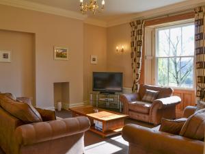 a living room with leather furniture and a flat screen tv at Langdale Crag in Grasmere