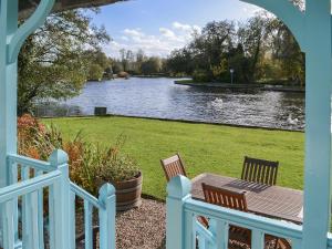 a porch with two chairs and a table next to a lake at Leisure Hour in Wroxham