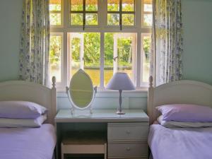 a bedroom with two beds and a mirror and a window at Leisure Hour in Wroxham