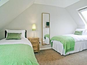 a white bedroom with two beds and a mirror at Blackmill Cottage in Taynuilt