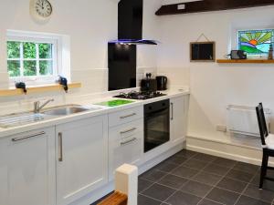 a white kitchen with a sink and a stove at Oak Apple Cottage in Upottery