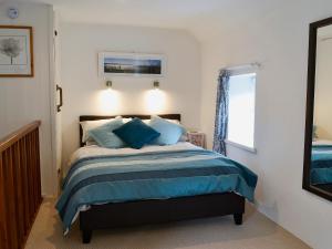 a bedroom with a bed with blue pillows and a mirror at Oak Apple Cottage in Upottery