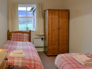 1 dormitorio con 2 camas, vestidor y ventana en Birch Tree Cottage en Aviemore