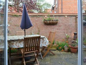 a table and chairs with an umbrella on a patio at Trentham Cottage in Snettisham