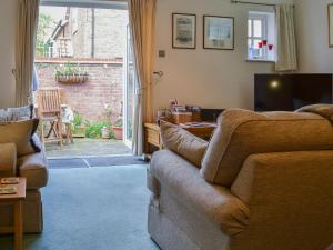 sala de estar con sofá y TV en Trentham Cottage, en Snettisham