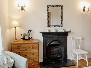 a room with a fireplace and a mirror on a dresser at Heathfield in Denholm