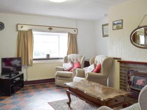 a living room with two chairs and a fireplace at Ty-gwyn in Brondini