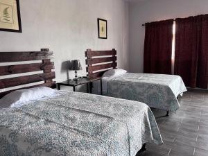 1 dormitorio con 2 camas y mesa con lámpara en Wally’s Place, en Estelí