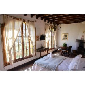 1 dormitorio con cama, mesa y ventanas en Hostal Los Castaños, en San Alfonso