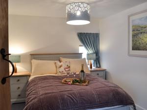 a bedroom with a bed with a tray with wine glasses at Bramble Cottage Mountain Retreat in Twyn Llanan
