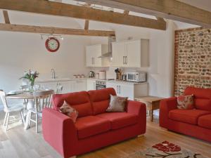 a living room with two red couches and a kitchen at Owl'S Roost in Edingthorpe