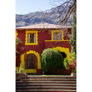 a red and yellow house with stairs in front at Hostal Los Castaños in San Alfonso