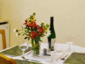 a table with a vase of flowers and a bottle of wine at River Wye View Cottage in Symonds Yat