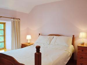 a bedroom with a bed with two lamps and a window at River Wye View Cottage in Symonds Yat