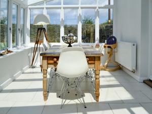 a dining room with a wooden table and a white chair at Pink Cottage in Little Walsingham