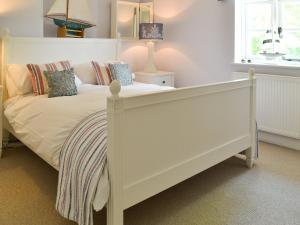 a bedroom with a white bed and a window at Pink Cottage in Little Walsingham