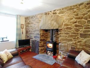 a living room with a stone wall with a wood stove at Gracedieu in Killin