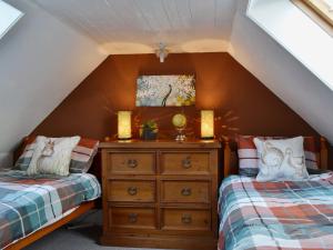 a attic bedroom with two beds and a dresser at Gracedieu in Killin