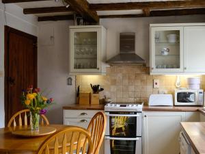 a kitchen with white cabinets and a table with a vase of flowers at Foss Gill in Starbotton