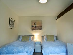 a bedroom with two beds and a painting on the wall at Moorland Retreat in Barbrook