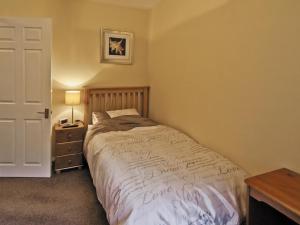 a bedroom with a bed and a table and a door at Llamedos - Hw7771 in Llandudno