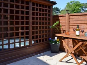 a patio with a wooden fence and a table with wine glasses at Banovallum Cottage in Horncastle