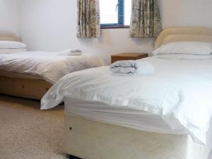 a bedroom with two beds with white sheets and a window at Jebel Kasr in Braithwaite