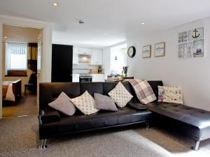a black leather couch with pillows in a living room at Devon Villa Garden Apartment in Torquay