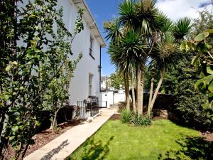 a garden with palm trees and a white house at Devon Villa Garden Apartment in Torquay