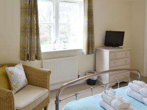 a bedroom with a bed and a chair and a window at Teal Cottage in Embleton