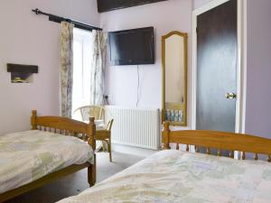 a bedroom with two beds and a tv on the wall at Wheelwrights in East Down